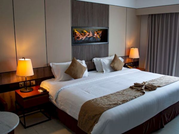A modern hotel room with a large bed, two lamps, a table, and a decorative wall feature, creating a cozy and elegant atmosphere.