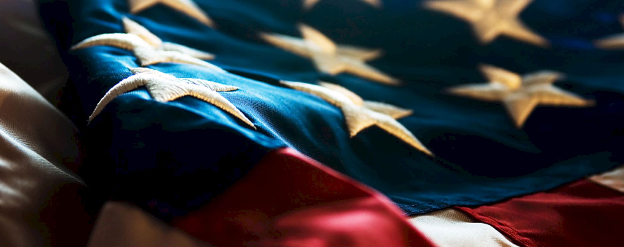 An American flag with visible stars and stripes is shown, focusing on the blue field and white stars.