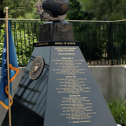 A monument with an eagle, globe, and anchor atop a pedestal, featuring engraved names and a flag beside it.