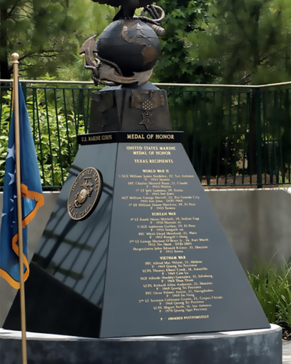 A monument featuring an eagle globe and anchor, with a plaque listing Medal of Honor recipients. A flag stands beside it.